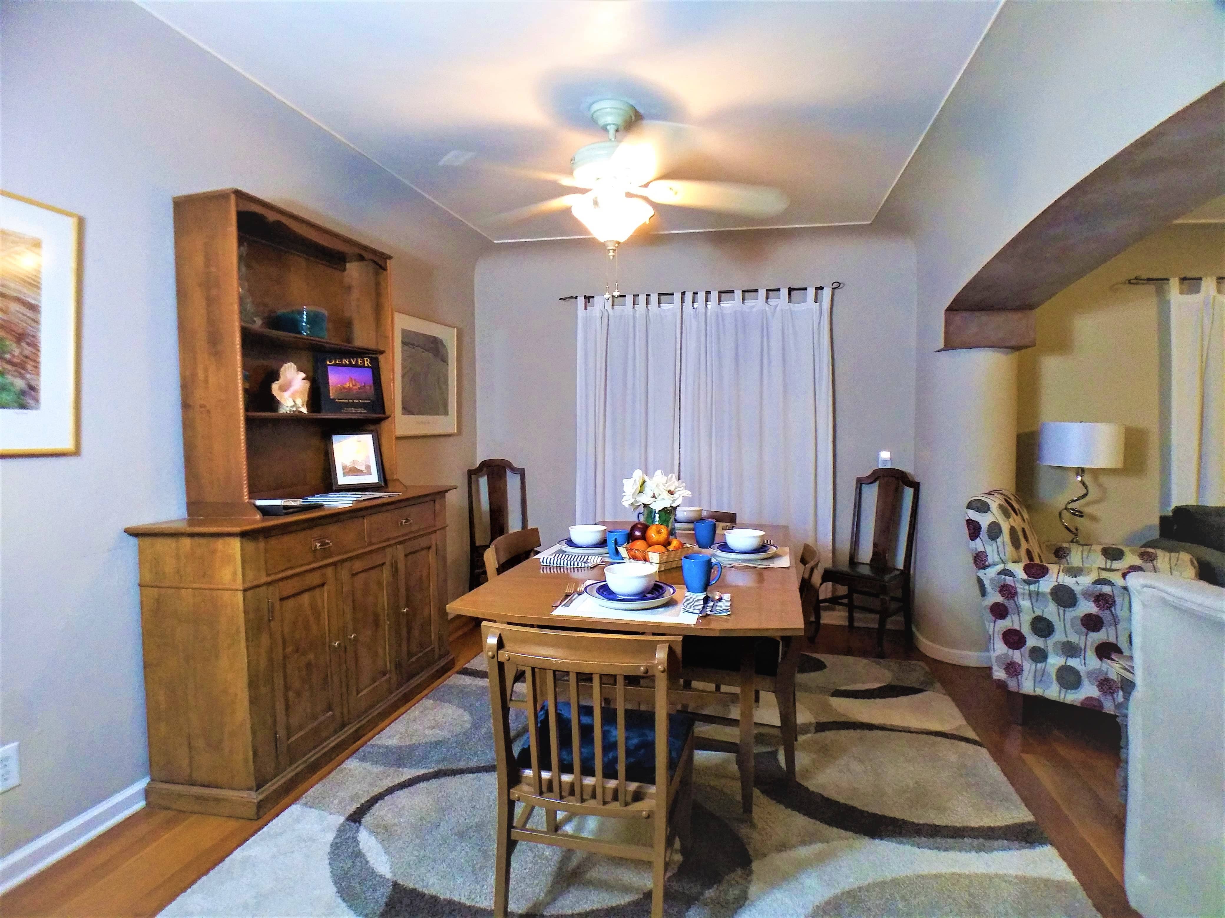 Large living room with a large dining table, magazines, and table set with dishes for 4